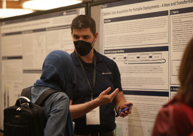 A presenter explains a poster to a colleague at the SSA Annual Meeting 2023