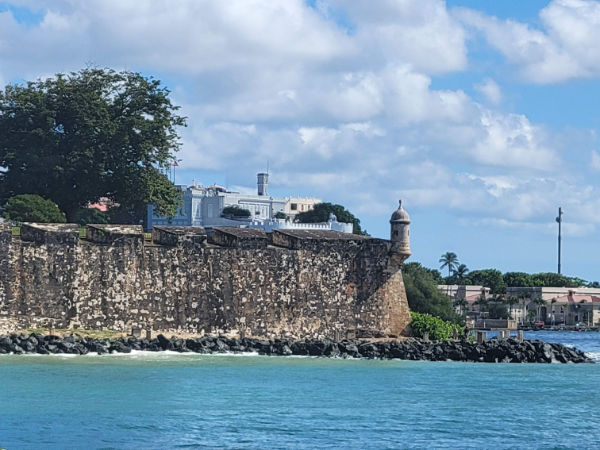 A bright light colored building atop a sea wall in Puerto Rico